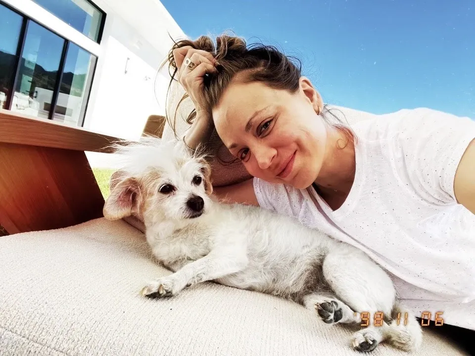 Kaley Cuoco lying down beside a small white dog, promoting the 12th Annual Remember Me Thursday® animal welfare campaign.